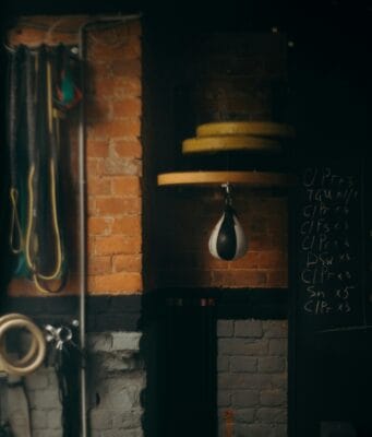 Home Fitness Corner Makeovers: Before and After Dimly lit boxing gym interior with punching bag and workout equipment, evoking a vintage training vibe.